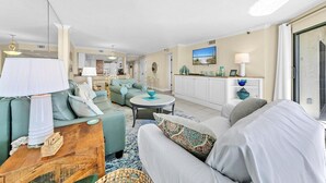 A spacious living room with a sofa set, a dining area, and a kitchen in the background. - Inlet Reef 215 (Destin)