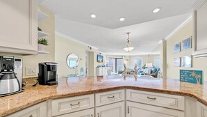 A spacious kitchen with white cabinetry, granite countertops, and a coffee maker. - Inlet Reef 215 (Destin)
