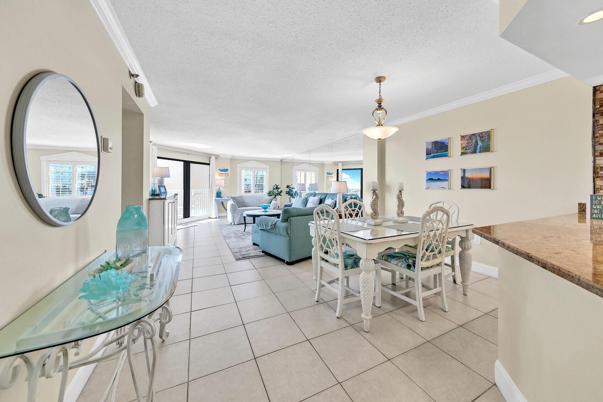 A spacious living area with a dining table, chairs, and a glass coffee table.