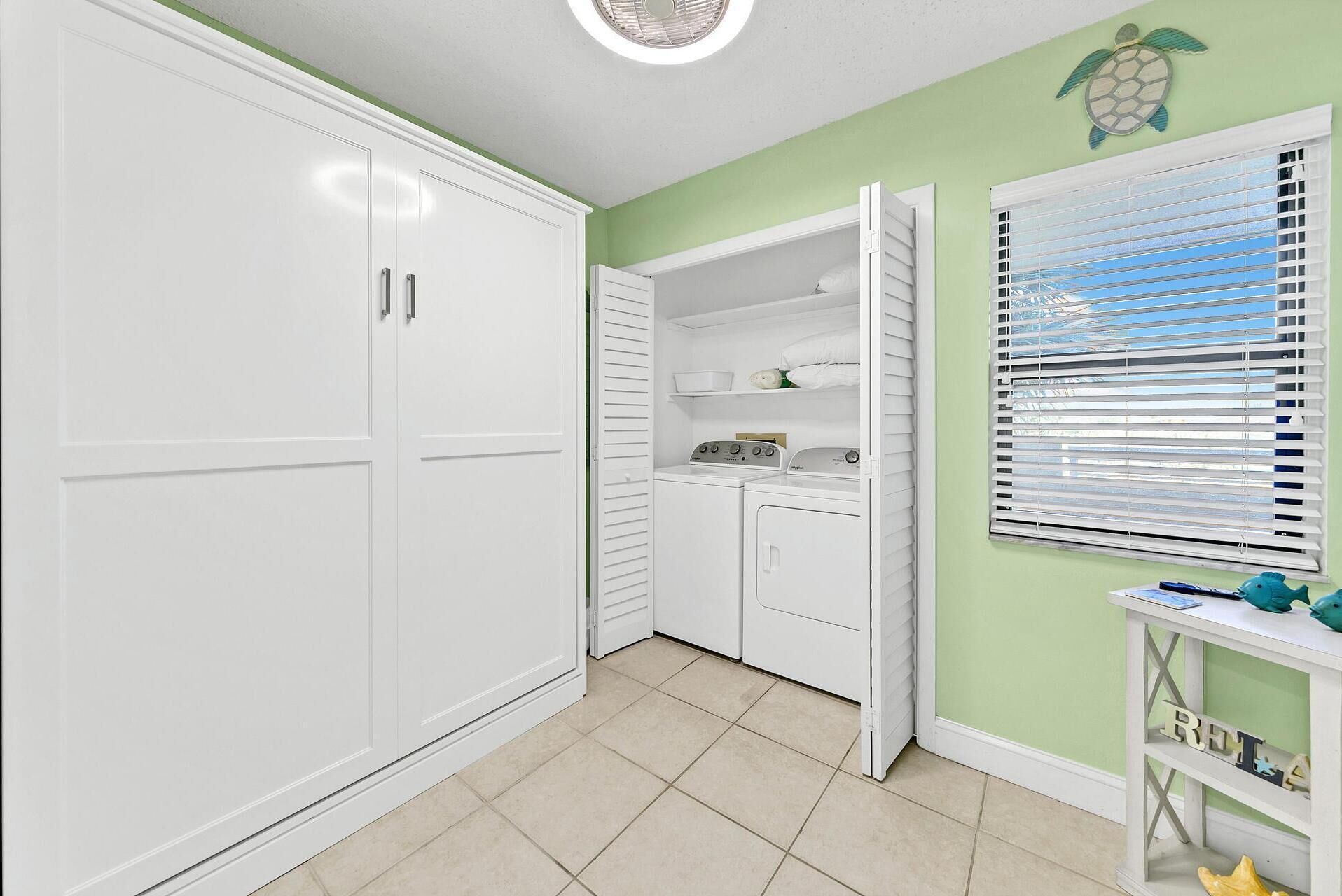 A laundry room with a washing machine, dryer, and storage cabinets.