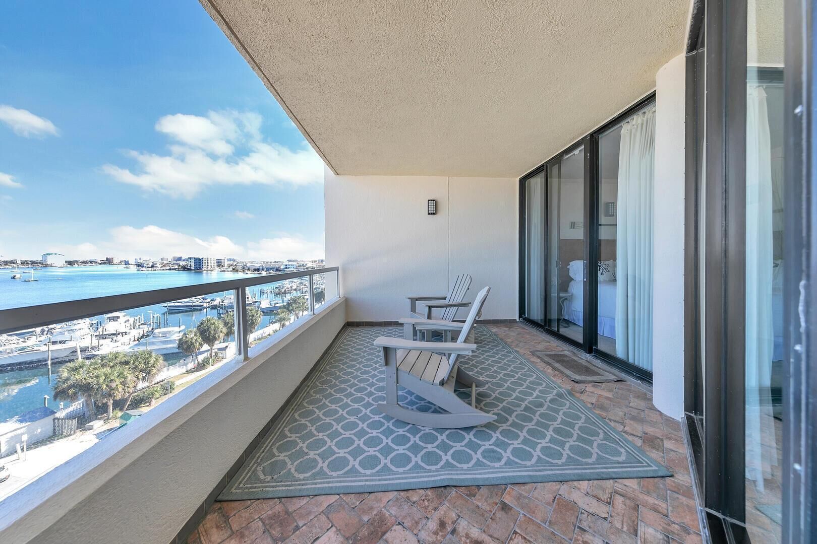 A balcony with a view of a marina and cityscape, featuring a small table and two chairs.