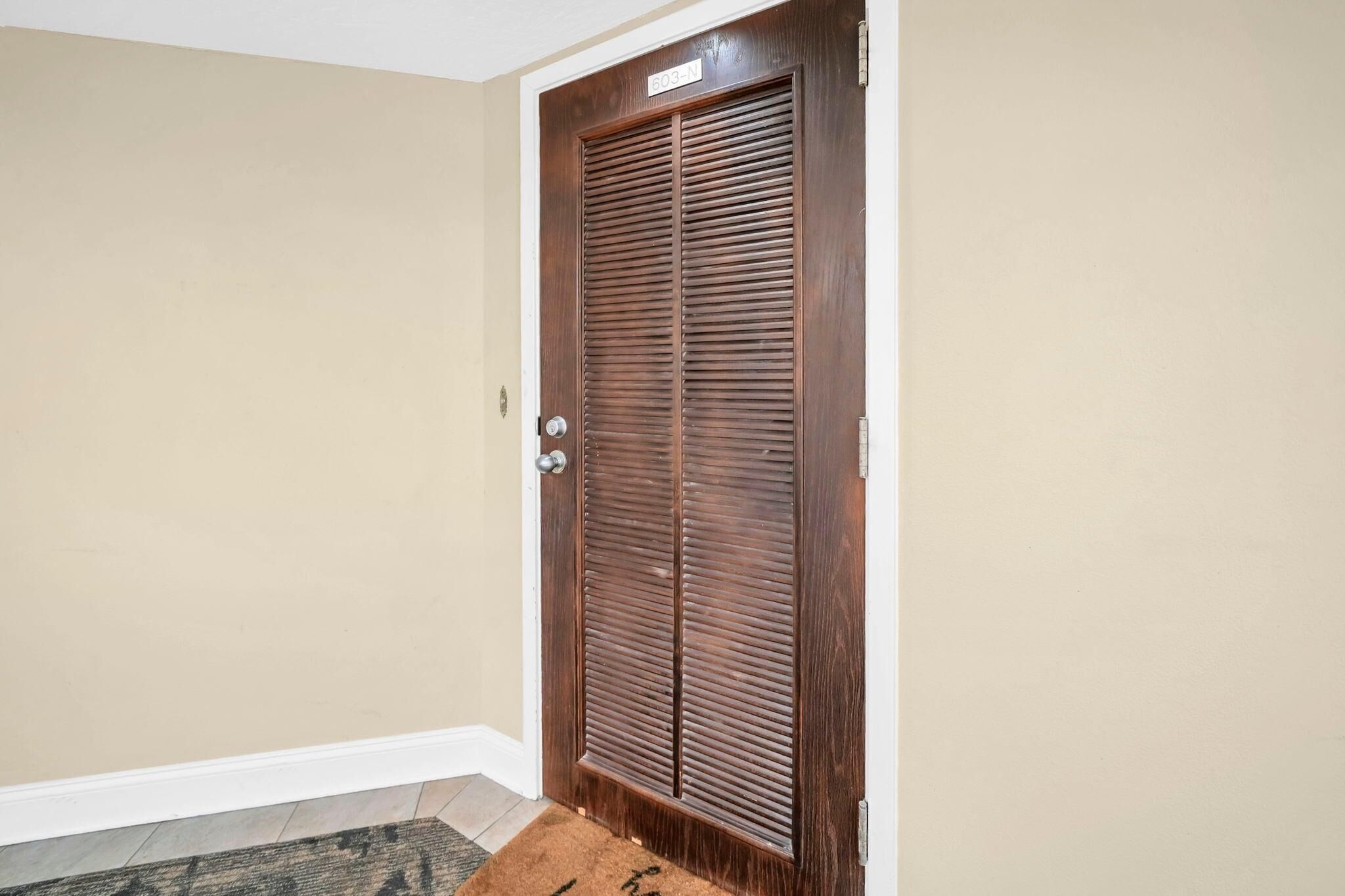 A closed wooden door with a metal handle and a number plate.