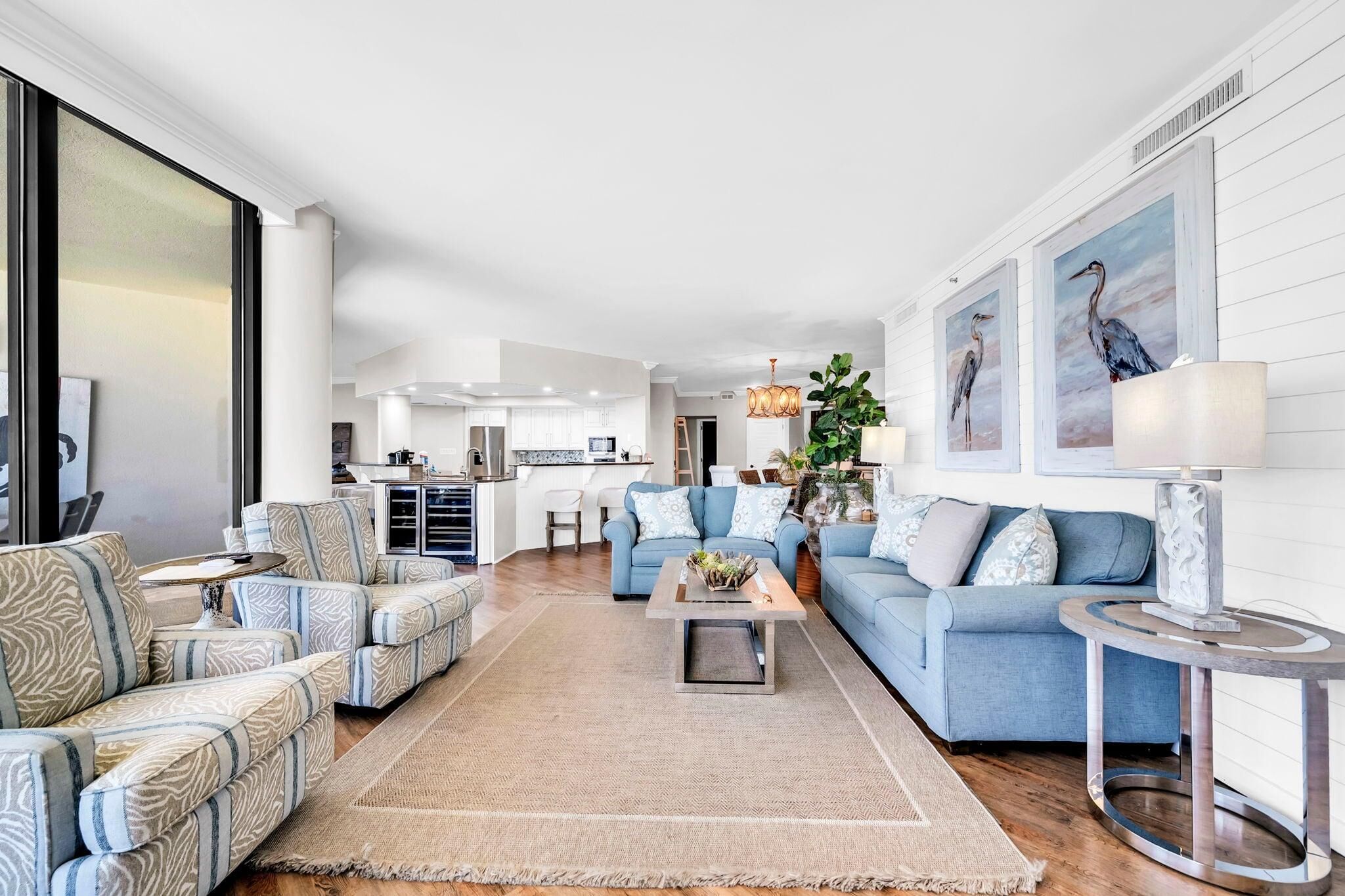 A spacious living room with a sofa set, a coffee table, and a dining area in the background.