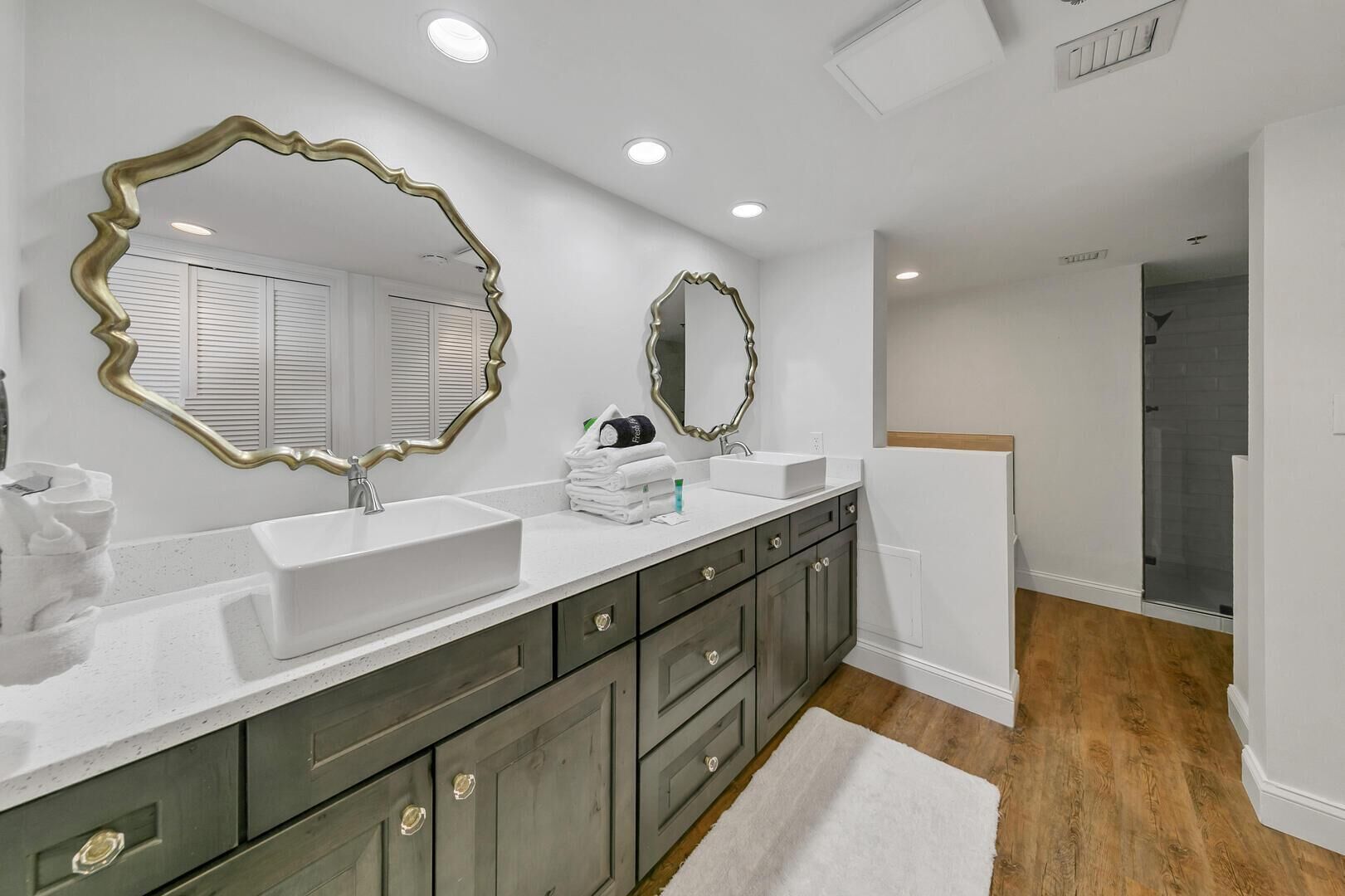 A modern bathroom with two sinks, large mirrors, and a walk-in shower.