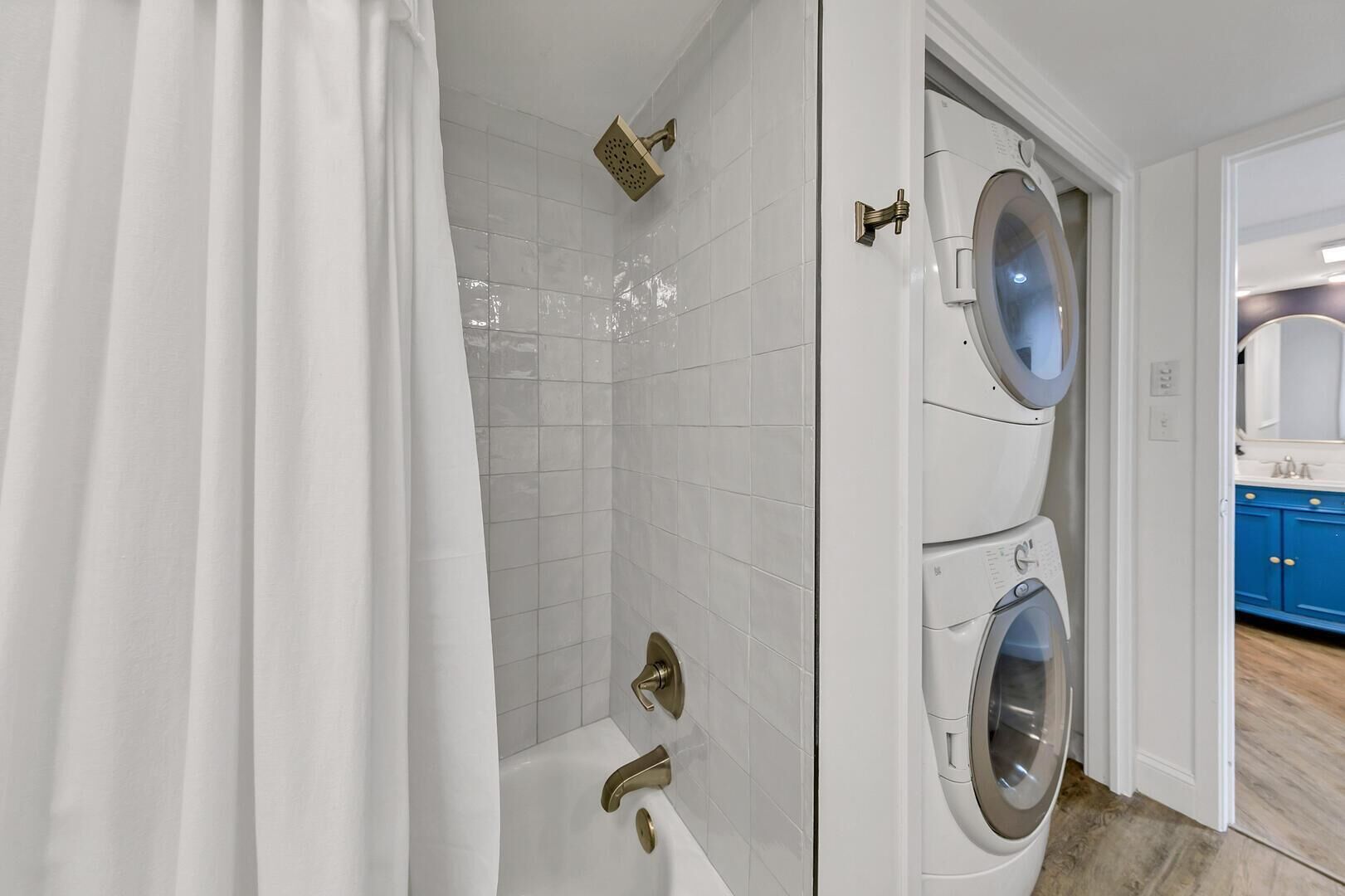 Une salle de bain équipée d’une douche, d’une baignoire et d’un lave-linge double.