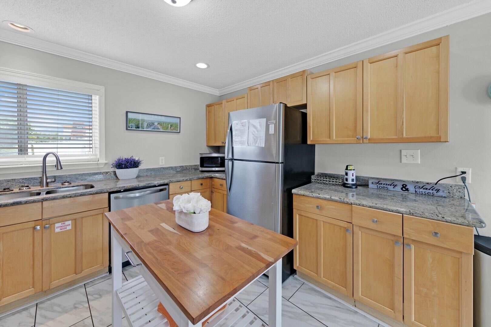 A modern kitchen with wooden cabinets, stainless steel appliances, and a granite countertop.