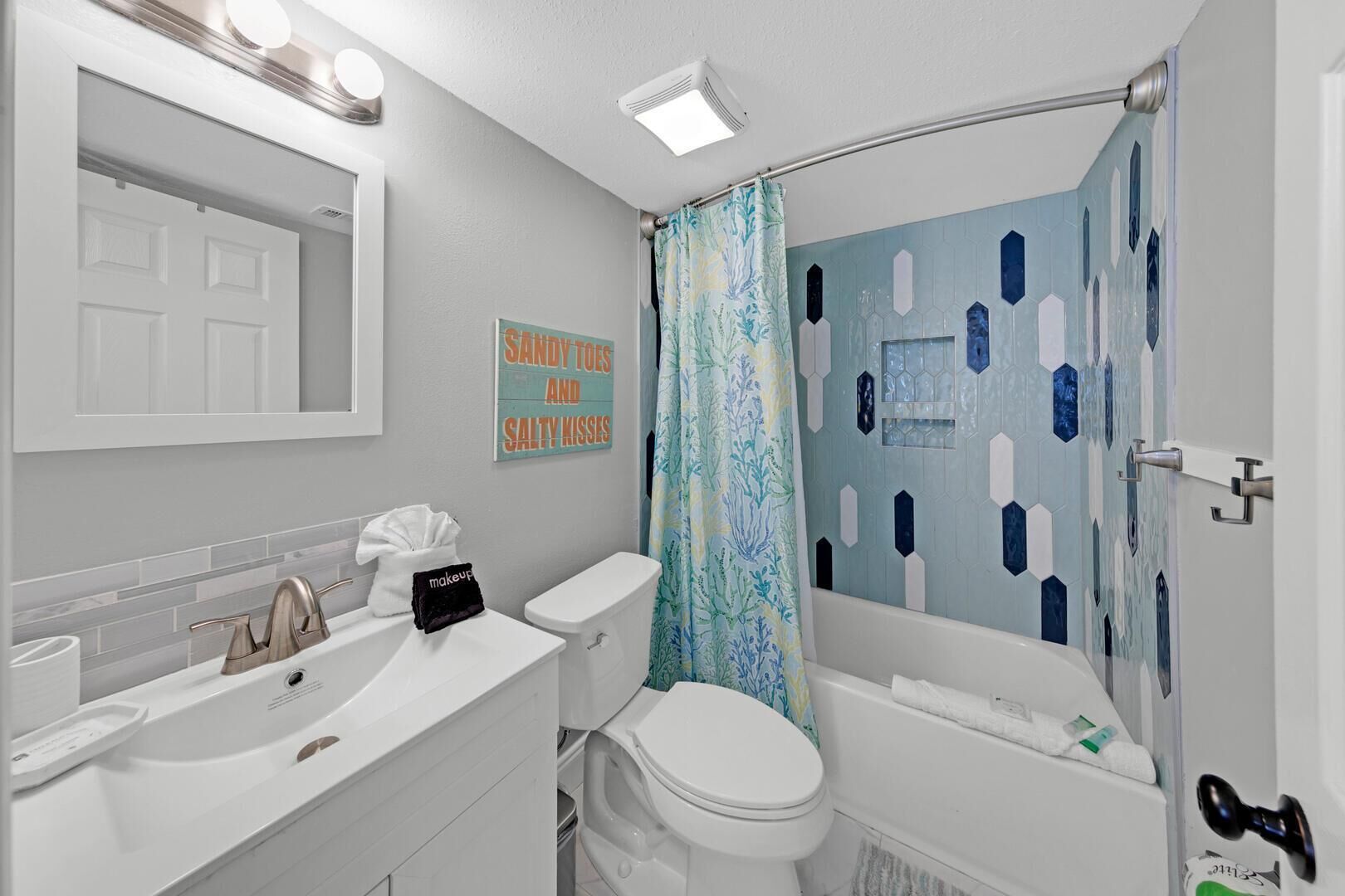 A bathroom with a white sink, a toilet, a bathtub, and a shower curtain with a geometric pattern.