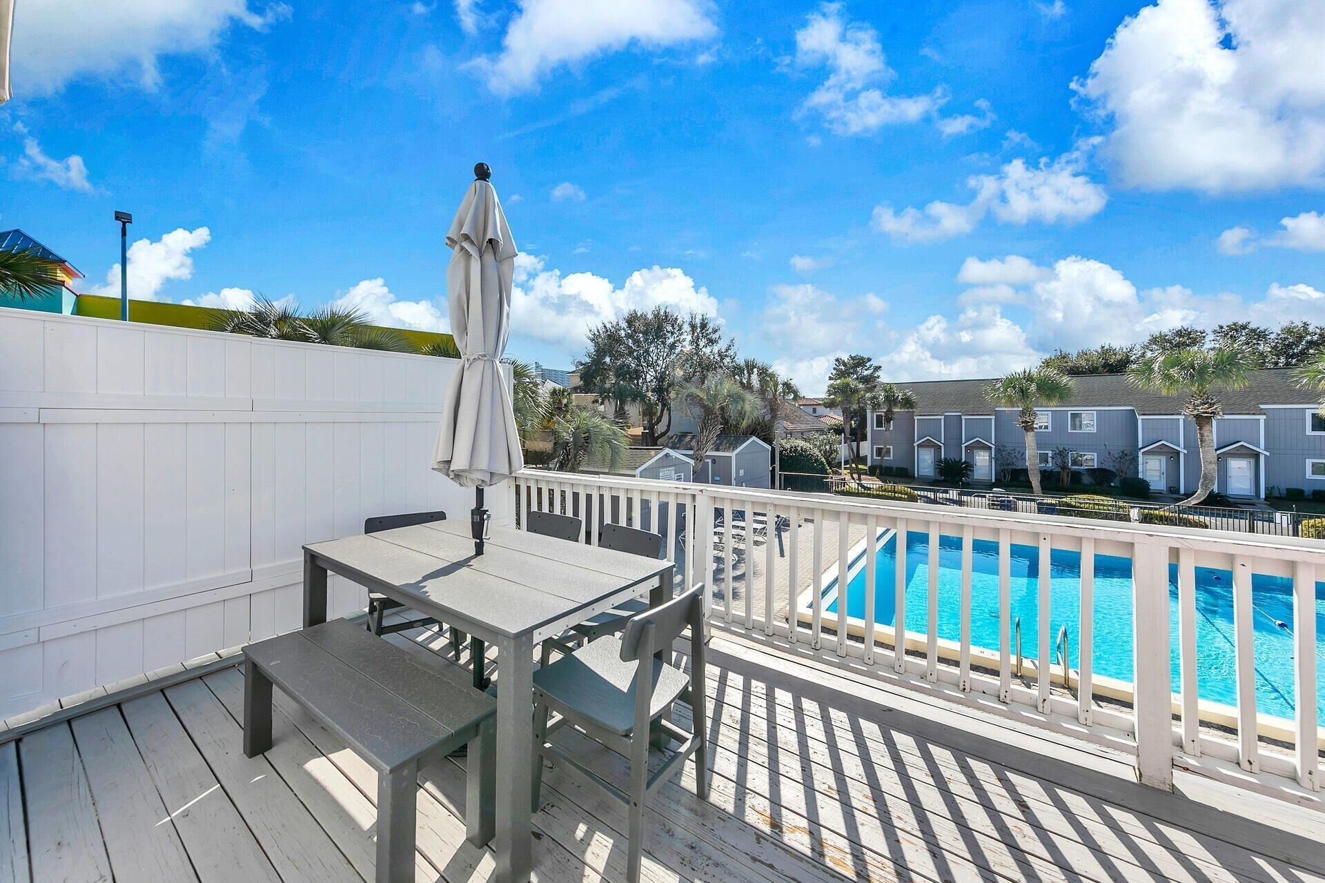 A wooden deck with a pool, a table, and chairs.