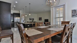 A spacious dining area with a large wooden table, multiple chairs, and pendant lighting. - Playa Blanca (Miramar Beach)