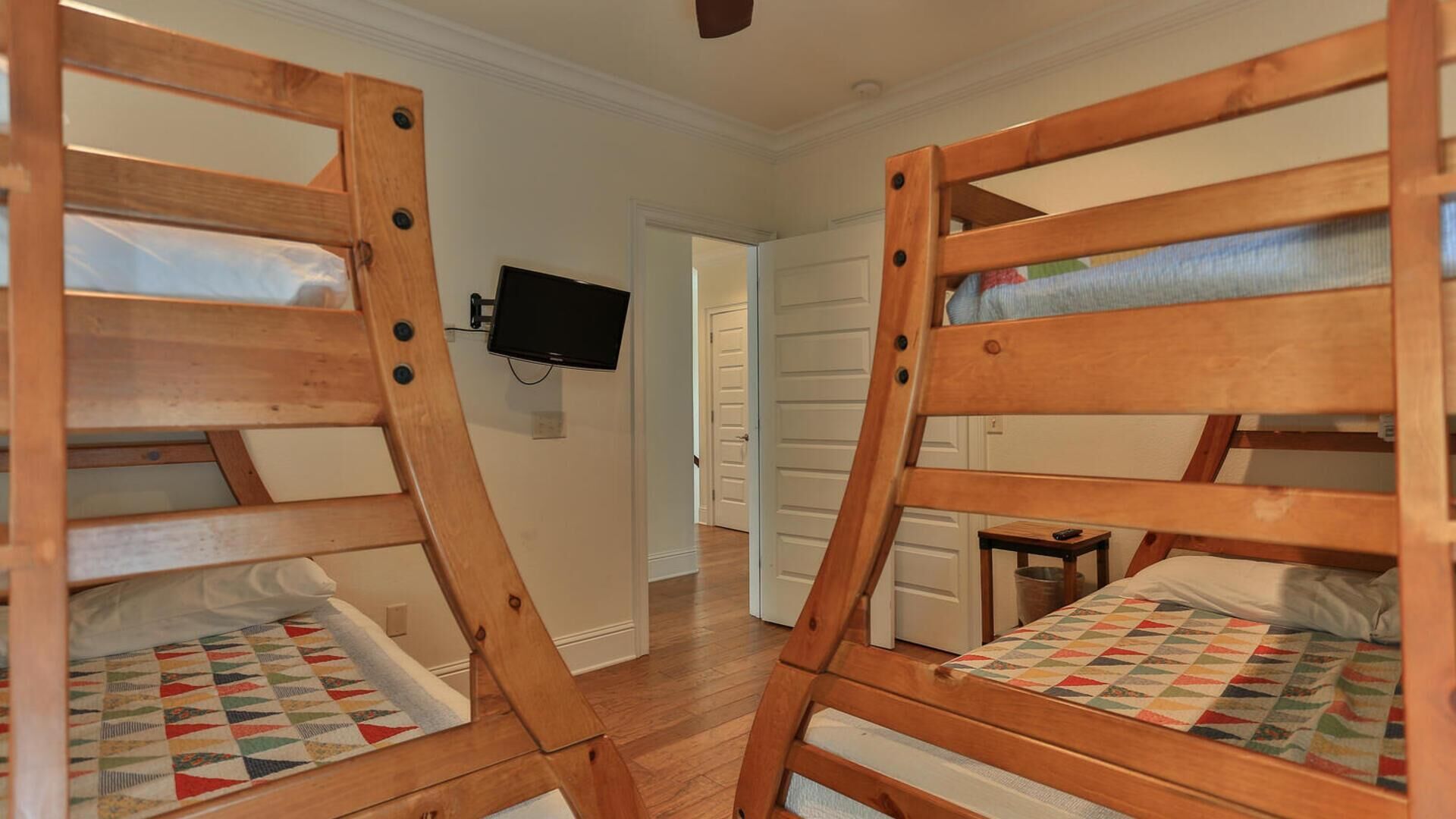 Una habitación con dos literas de madera, un televisor en la pared y un pasillo que conduce a otra habitación.