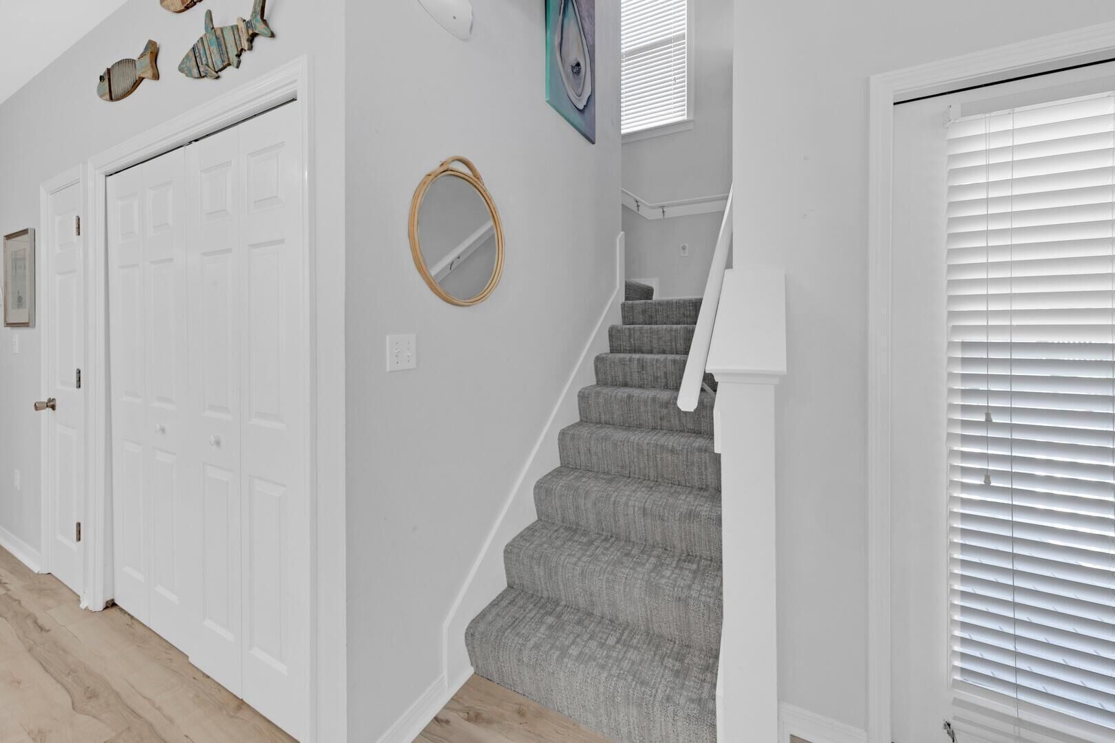 A hallway with a staircase, white walls, and a door.