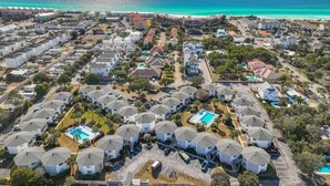 A coastal residential area with multiple houses, a swimming pool, and a view of the ocean. - Crystal Village II, Unit 6B (Miramar Beach)