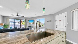 A modern kitchen with a large island, a built-in sink, and pendant lighting. - Crystal Village II, Unit 6B (Miramar Beach)