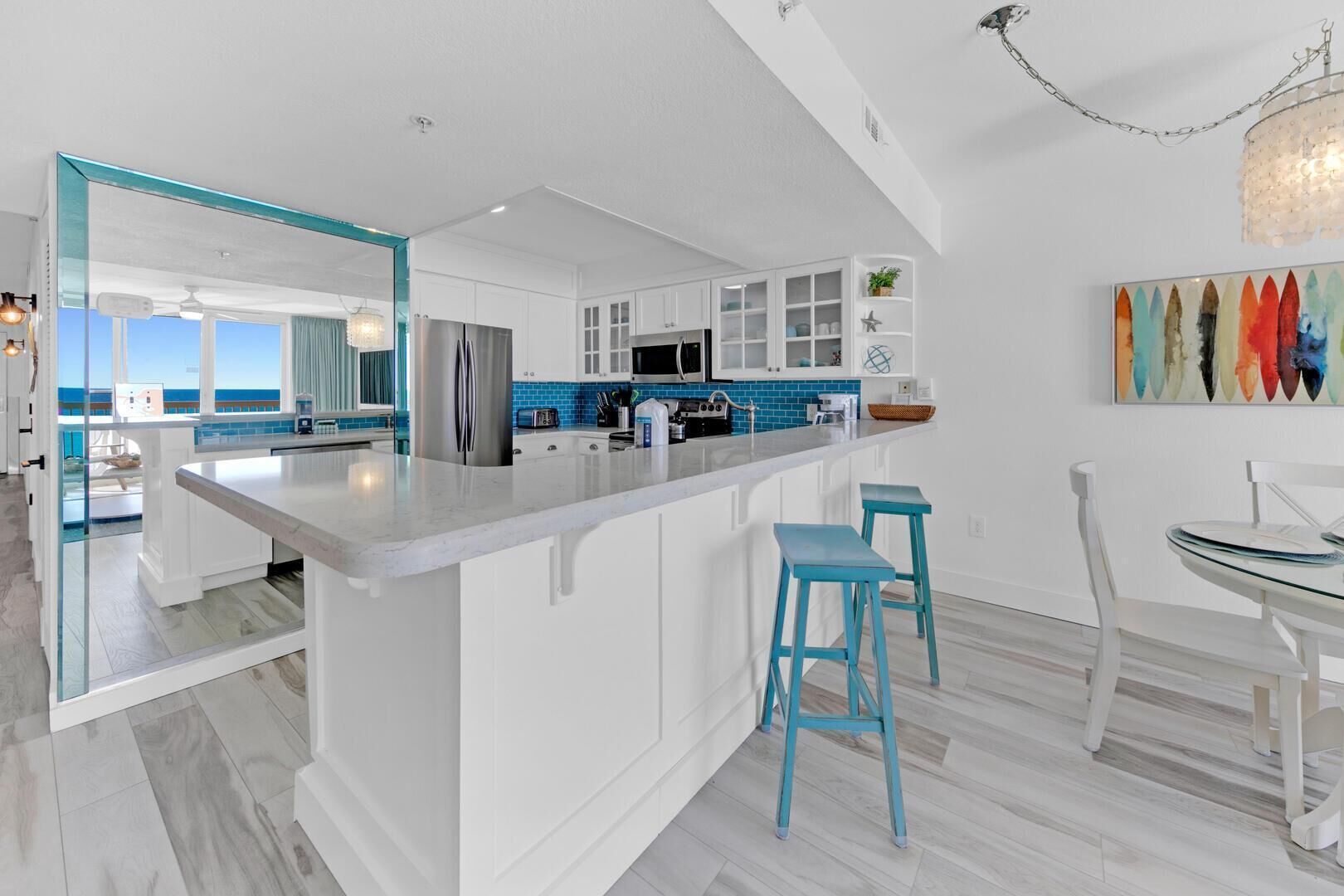 A modern kitchen with white cabinetry, a large island, and blue accents.