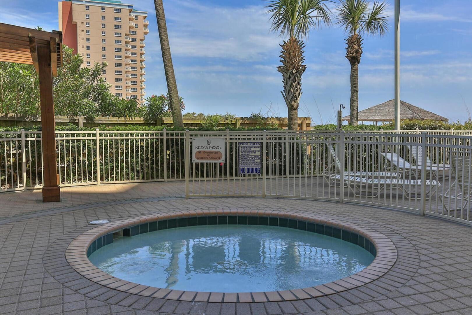 A pool area with a sign indicating it is a kid's pool, no diving allowed, and grown-ups and diapers are allowed.