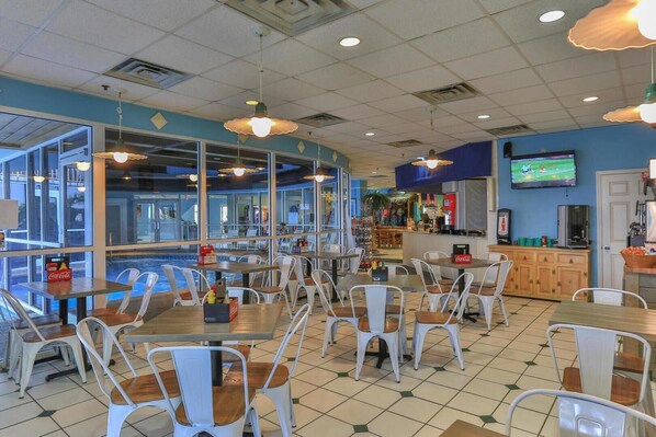 A restaurant with indoor seating, a pool view, and a bar area. - Pelican Beach 307 (Destin)