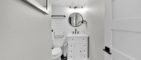 Un baño estrecho con inodoro, lavabo y espejo.