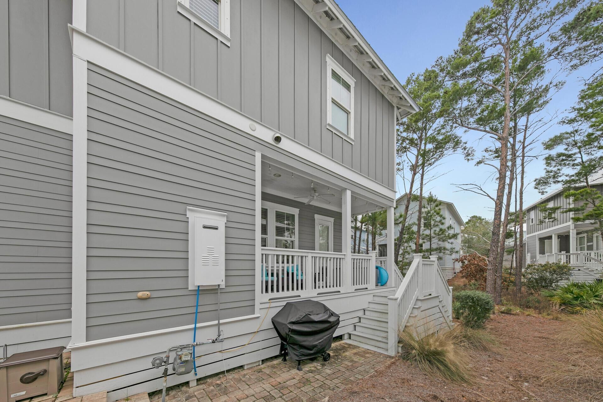 A two-story house with a covered porch and a small outdoor grill.