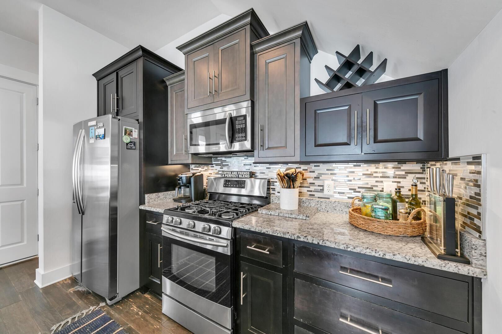 A modern kitchen with dark cabinetry, stainless steel appliances, and a tiled backsplash.