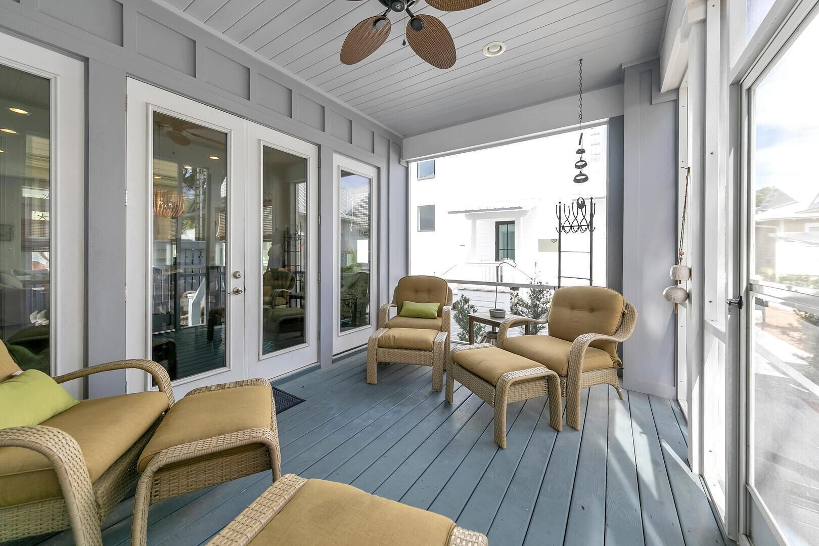 A covered porch with wicker furniture and a view of a house.