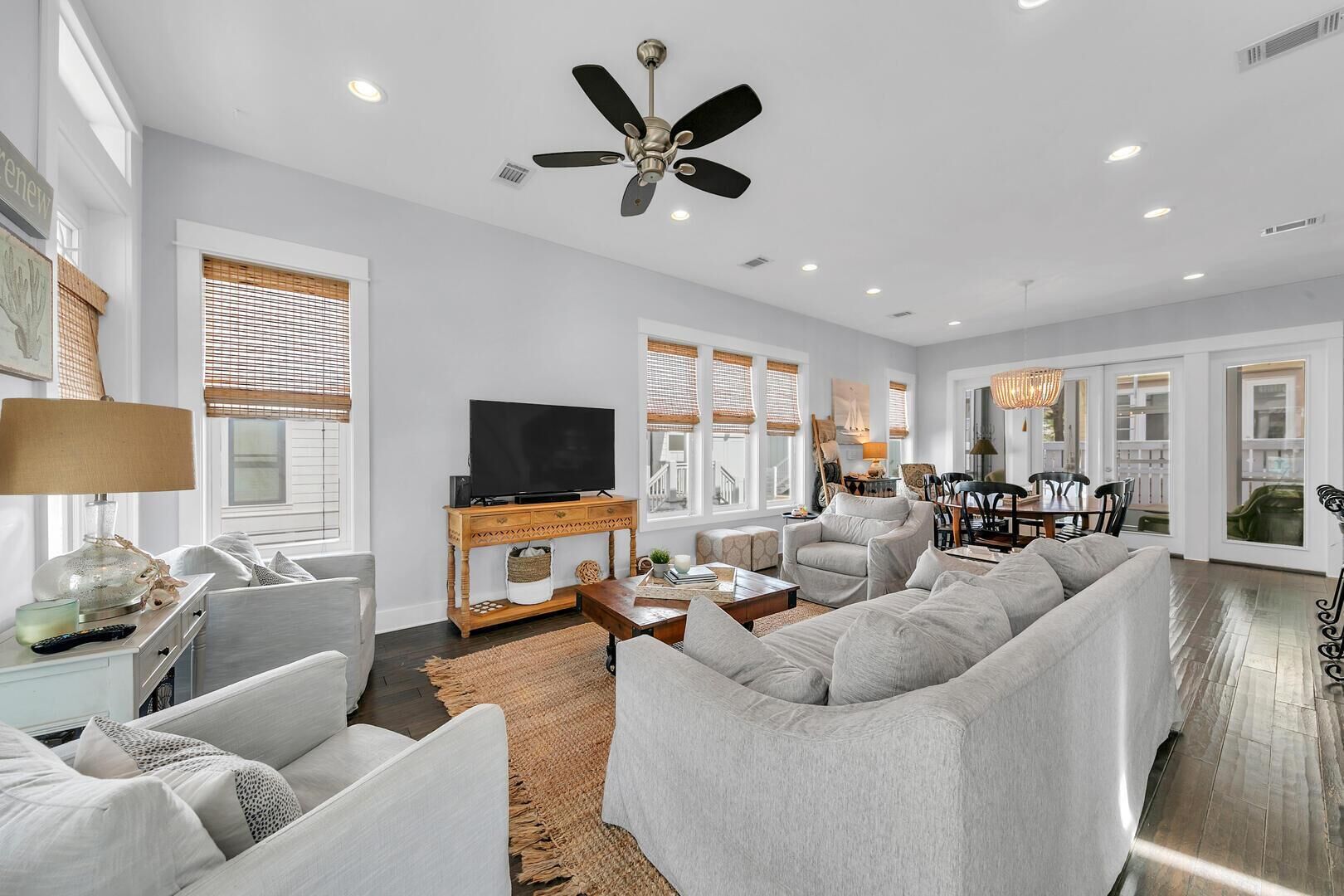 A spacious living room with a large sofa, a television on a wooden stand, and a dining area with a table and chairs.