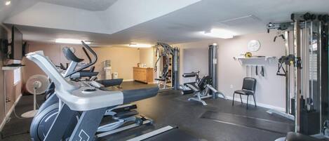 A gym with treadmills, weight machines, and a fan.