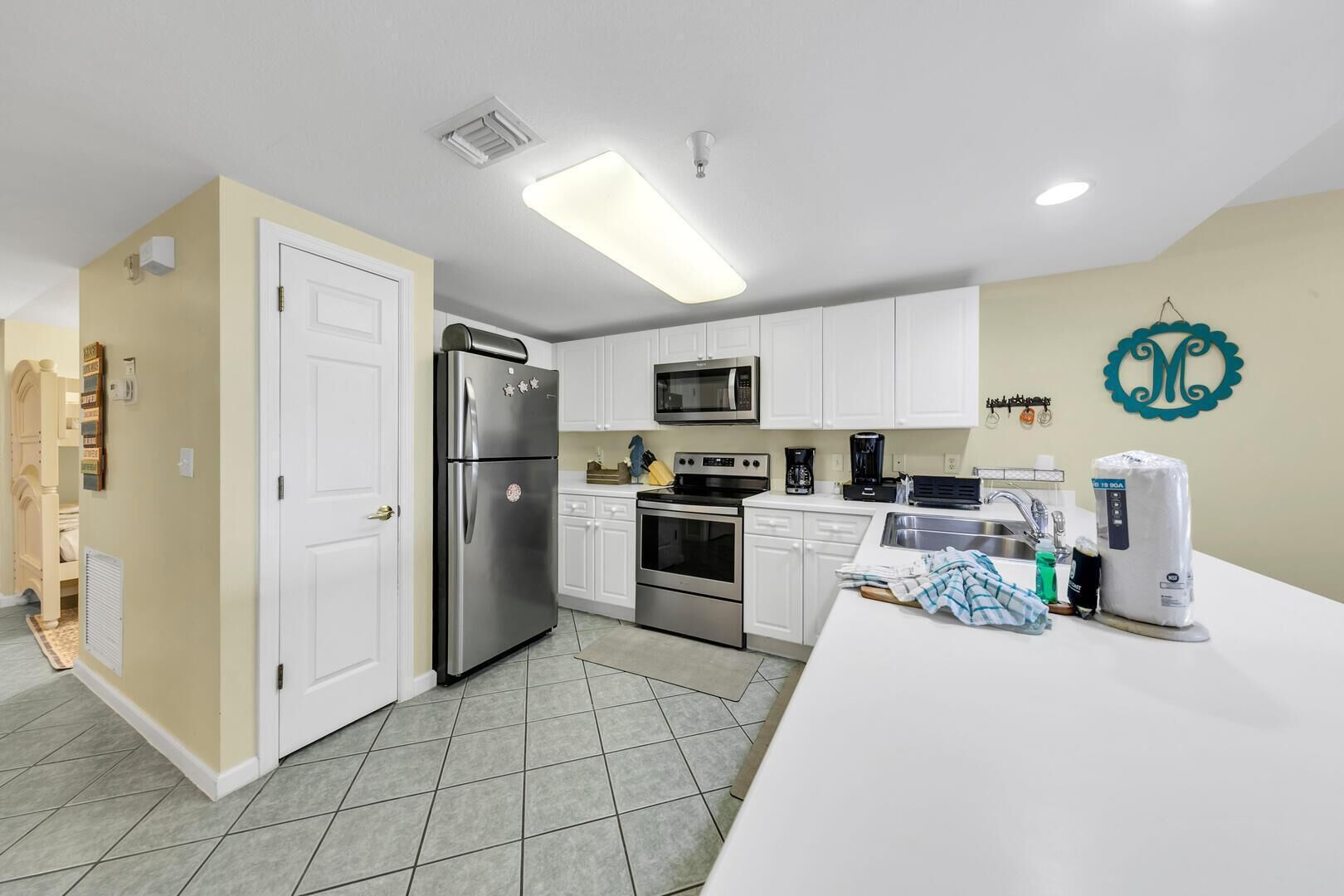 A modern kitchen with white cabinets, stainless steel appliances, and a tiled floor.
