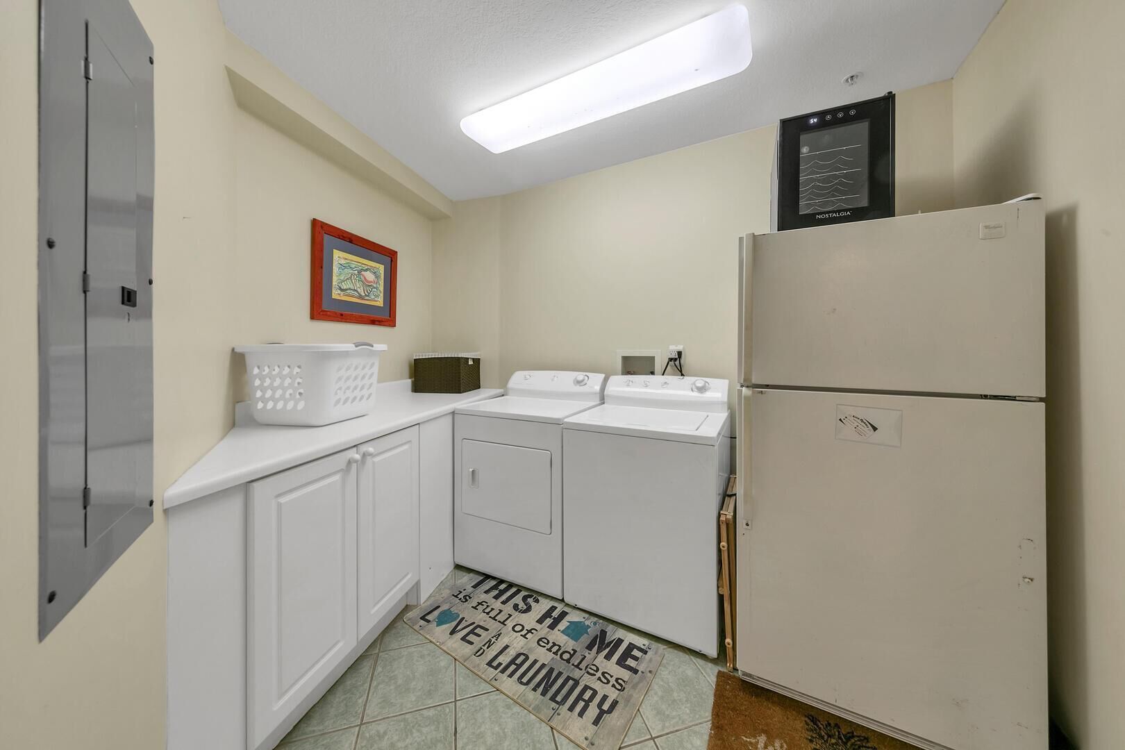 A laundry room with a washing machine, dryer, and a refrigerator.