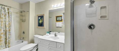 A bathroom with a toilet, sink, and shower.