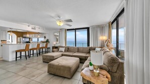 A modern living room with a large sectional sofa, a wooden coffee table, and a view of the ocean. - Mainsail 131 (Miramar Beach)