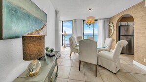 A modern living room with a dining area, a large abstract painting, a chandelier, and a view of the sea. - Mainsail 131 (Miramar Beach)