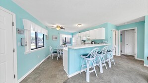 A kitchen with a bar area, white cabinets, and a ceiling fan. - Crystal Village II, Unit 18A (Miramar Beach)