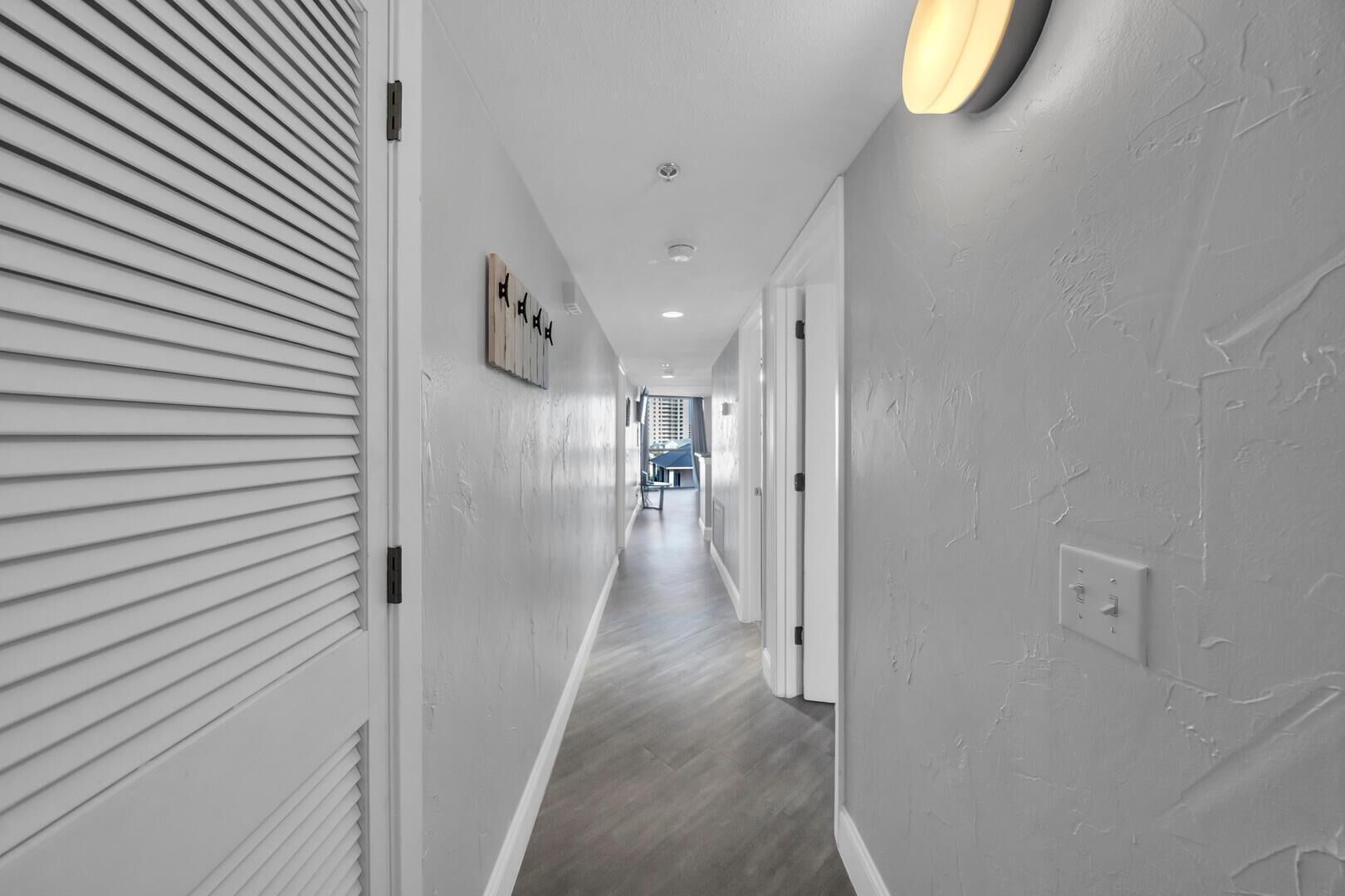 A hallway with white walls, a wooden floor, and a ceiling light fixture.