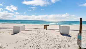 Une plage de sable blanc, un banc en bois et un panneau indicateur.