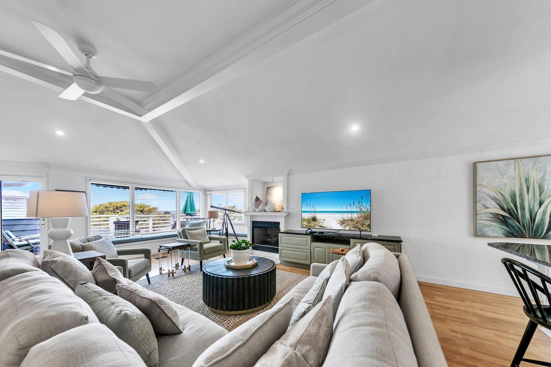 Un salon spacieux avec un grand canapé, une table basse et un téléviseur. Il y a une cheminée et un balcon avec vue.