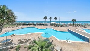 A pool area with lounge chairs and umbrellas, a beach in the background, and a clear blue sky. - Silver Beach Towers - Penthouse106e (Destin)