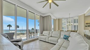 A spacious living room with a large sofa, a dining area, and a balcony with a view of the beach. - Silver Beach Towers - Penthouse106e (Destin)