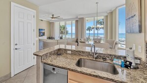 A modern kitchen with a granite countertop, stainless steel sink, and Bosch dishwasher. - Silver Beach Towers - Penthouse106e (Destin)