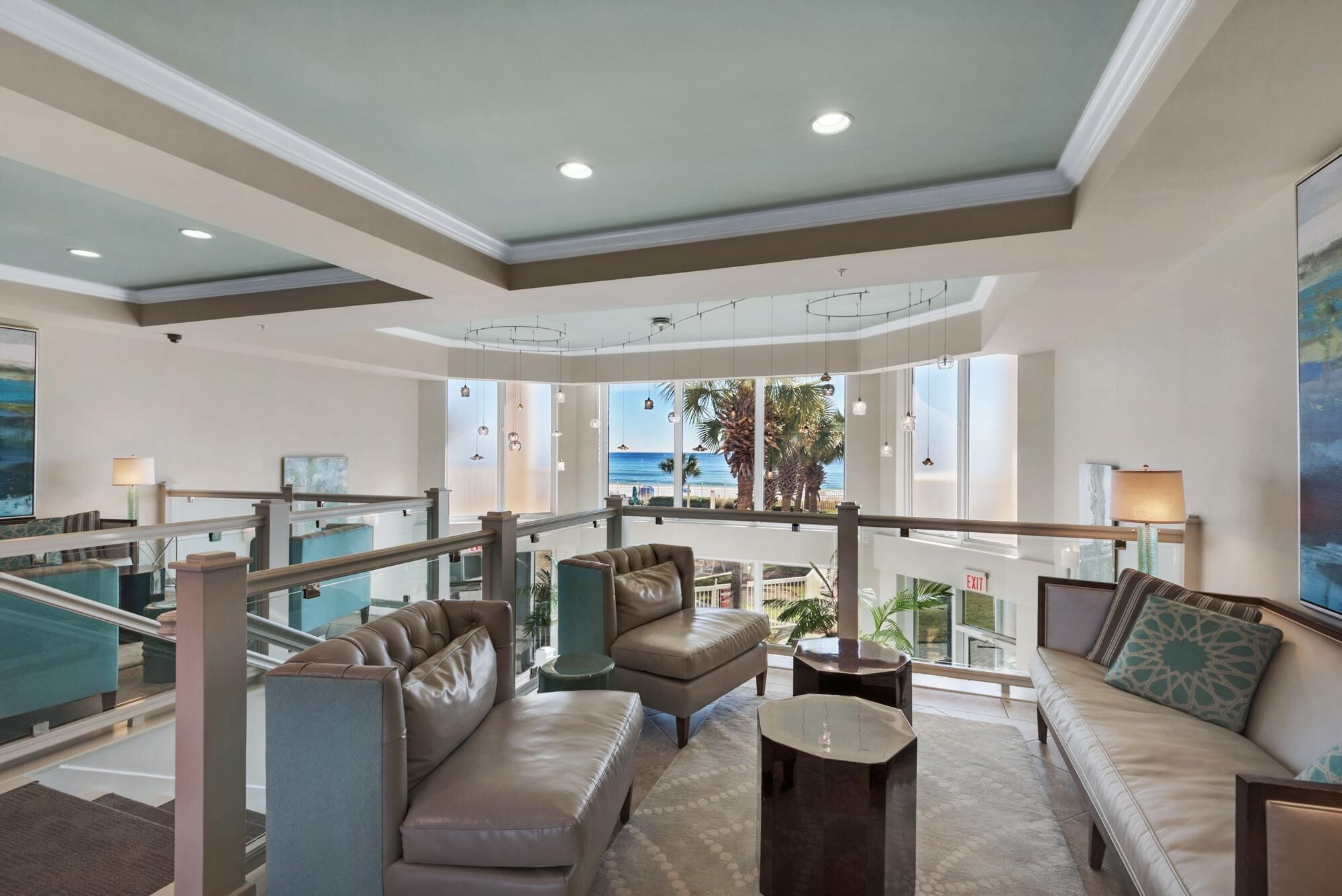 A spacious lobby with a high ceiling, a staircase, and a view of the ocean.