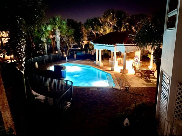 A swimming pool with a hot tub, surrounded by palm trees and a covered seating area. - Aqua Bella (Destin)