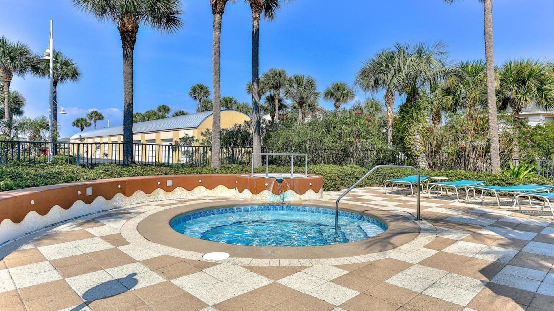 A swimming pool with a checkered tile pattern, surrounded by palm trees and lounge chairs.