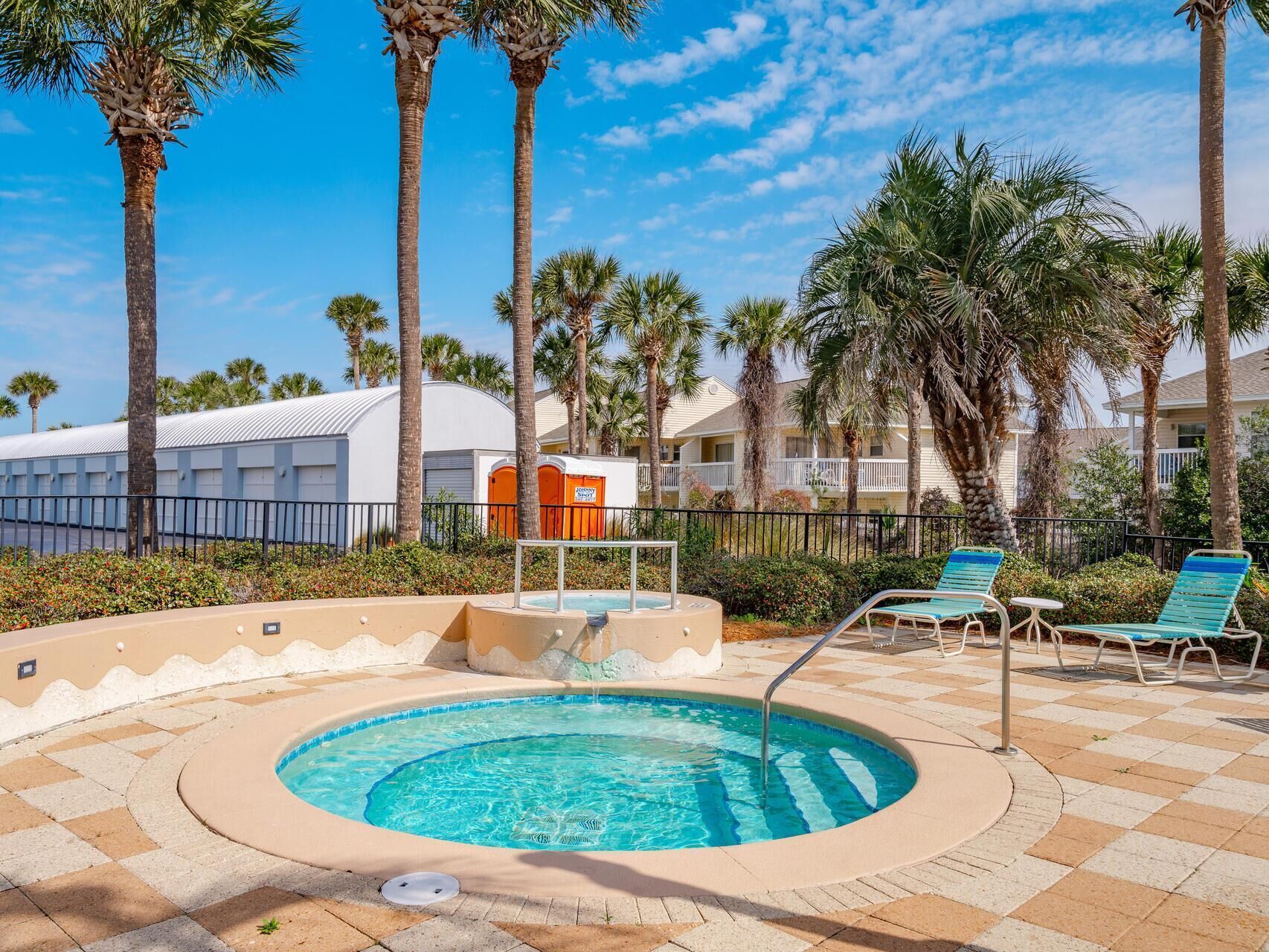 Un espace piscine doté d’un jacuzzi, de chaises longues et de palmiers.