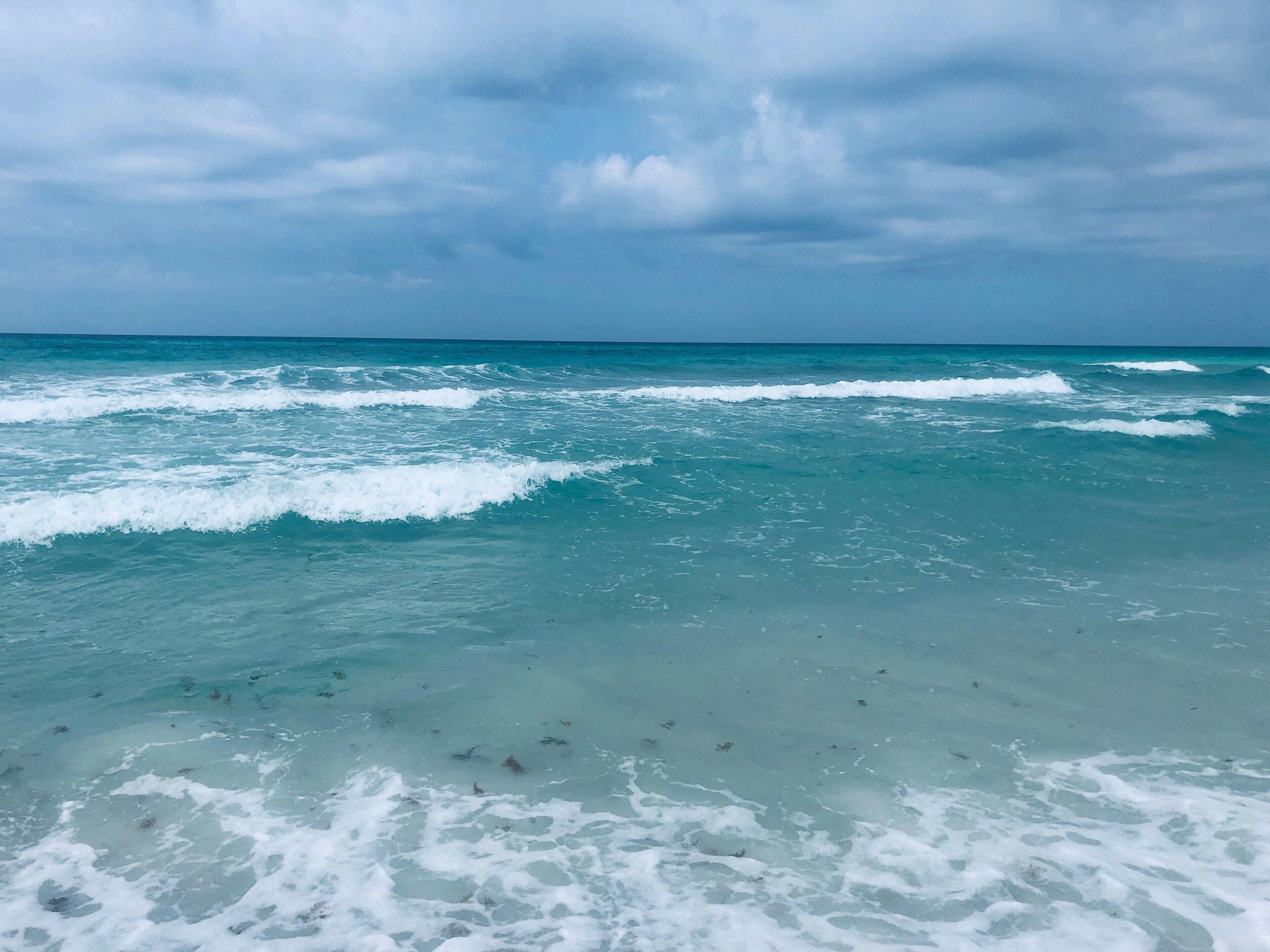 A beach with waves and a cloudy sky.