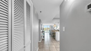 A hallway leading to a kitchen and dining area with a view of a pool. - Beachcrest 101 (Santa Rosa Beach)
