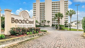 A beachfront condominium complex with a prominent sign, paved entrance, and palm trees. - Beachcrest 101 (Santa Rosa Beach)