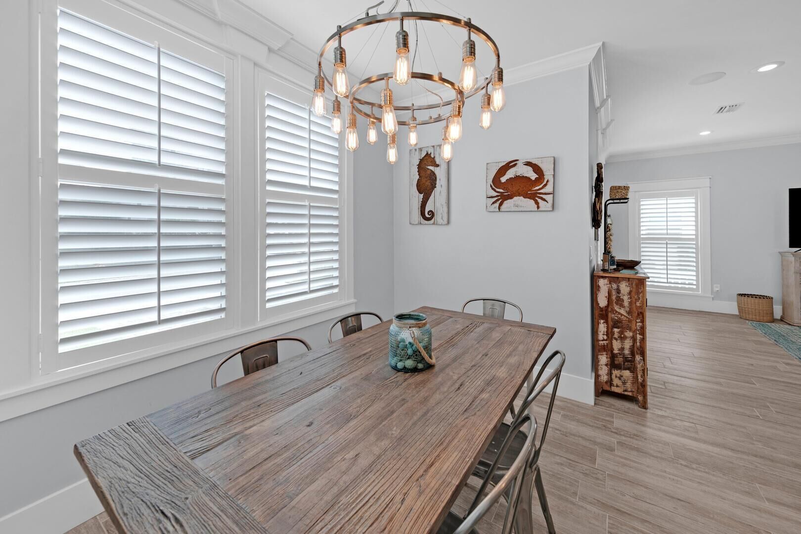 A spacious dining area with a wooden table, white walls, and a chandelier.