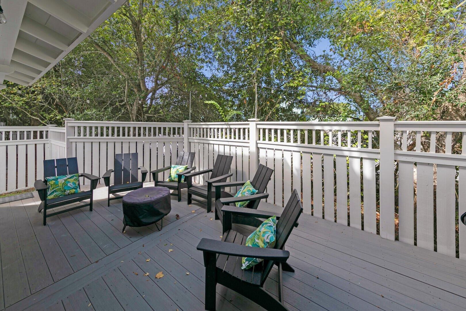 Eine Terrasse im Freien mit Holzmöbeln und einem weißen Zaun.