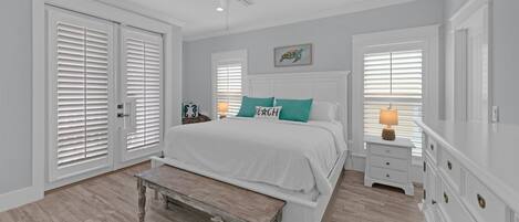 A bedroom with a bed, a bench, a nightstand, a dresser, a ceiling fan, and a window with blinds.