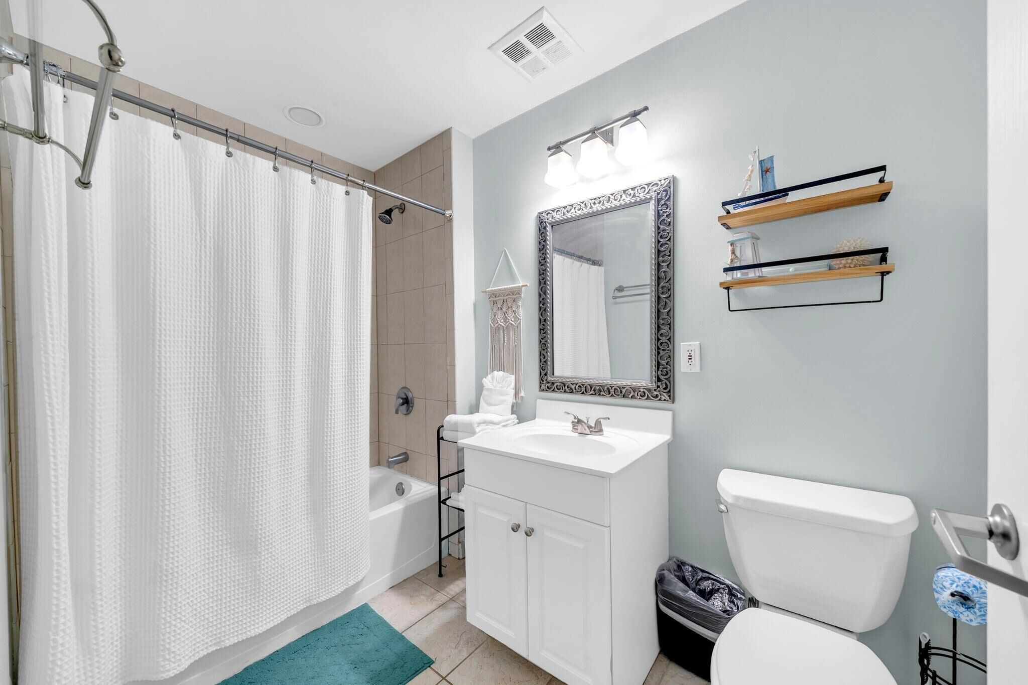 A bathroom with a shower, a sink, a toilet, and a mirror.