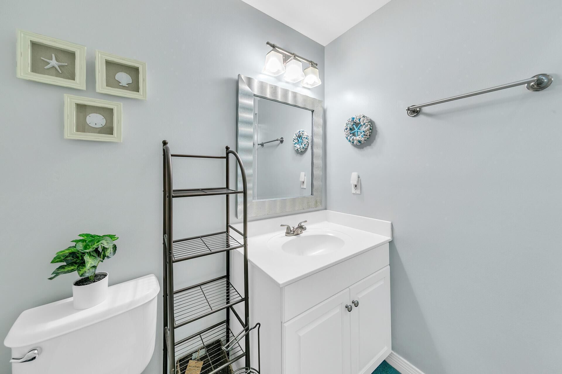 Une salle de bain avec un lavabo blanc, un miroir, un porte-serviettes et des toilettes.